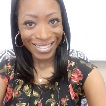 Una mujer de pelo negro y camisa de flores sonriendo cálidamente.
