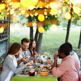 Una alegre reunión de personas que saborean una deliciosa comida al aire libre, rodeados de la belleza de la naturaleza.