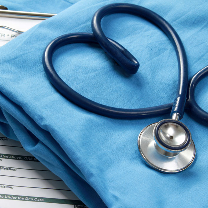 Un estetoscopio y un portapapeles en una hoja azul, que representan el examen médico y el mantenimiento de registros.