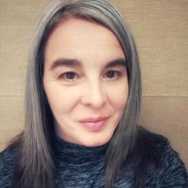 Una mujer de pelo gris con un top negro.
