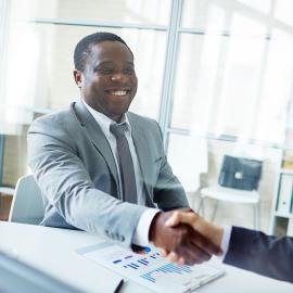 Dos profesionales dándose la mano en una oficina, sellando un trato.