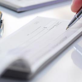 Una persona que escribe en un cheque con un bolígrafo.
