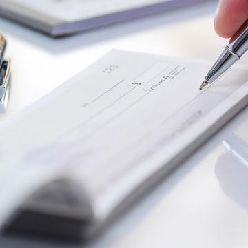 Una persona que escribe en un cheque con un bolígrafo.