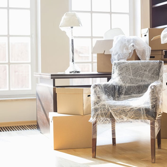 Una habitación desordenada con varias cajas y muebles dispuestos al azar.