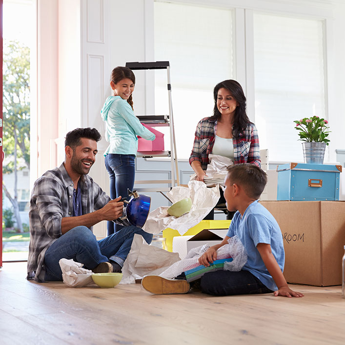Una familia feliz sentada en el suelo de su nuevo hogar, llena de emoción y alegría.