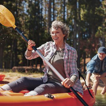 Una pareja mayor disfrutando de un sereno paseo en kayak por un lago tranquilo, rodeado de la belleza de la naturaleza.