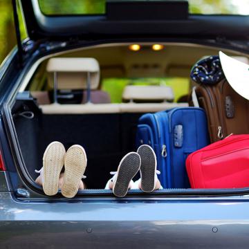 Una familia de cuatro personas sentada en el maletero de un coche, disfrutando juntos de un viaje por carretera.
