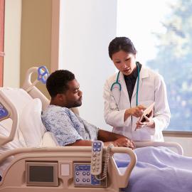 Un médico discutiendo con un paciente en una cama de hospital.